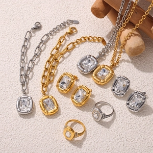 Minimalist gold and silver jewelry set with rectangular gemstones on beige textured surface