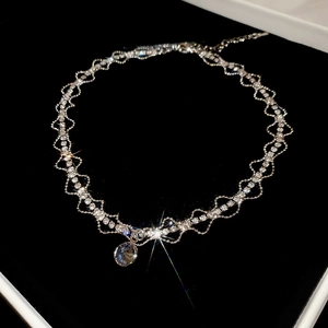 Macro view of sparkly silver circular pendant necklace with wave detail on black background