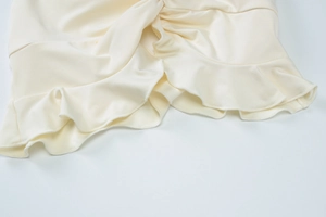 Close-up of ruffled cream fabric layers and precision stitching on the maxi dress