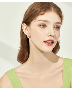 Close-up of golden moissanite leaf earrings worn by a model in natural light