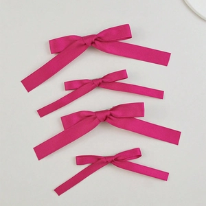 Detailed view of magenta satin bow hair clips in four sizes with metal backings