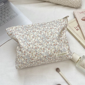 Macro detail of floral corduroy makeup bag with embroidery label and metal zipper