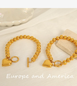 Detailed macro view of two golden beaded bracelets featuring smooth heart-shaped pendants