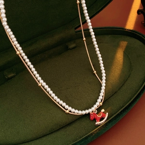 Detail of red enamel rocking horse pendant on pearl necklace with velvet box