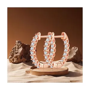 Elegant rose gold moissanite hoop earrings with pavé stones on natural rock display