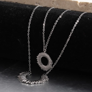 Detailed close-up of double-layer silver stainless steel necklace with sun pendants
