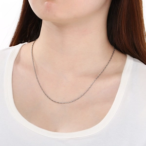 Détail d'un collier chaîne à billes minimaliste en acier inoxydable argenté sur modèle