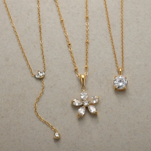 Detailed view of three gold-plated necklaces with flower and zircon crystal pendants