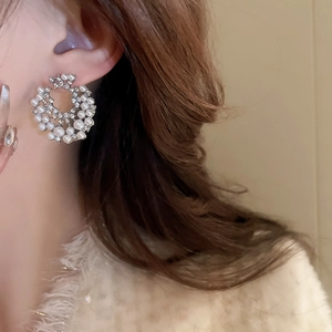 Gros plan sur boucle d'oreille géométrique argentée avec perles blanches et cristaux