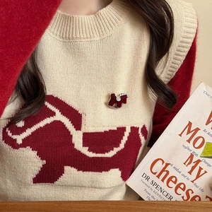 Detail der roten Pony-Brosche auf beiger Strickweste mit passendem Pferdemuster