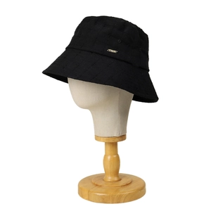 Quilted cotton linen bucket hat in black with metal logo detail on model head