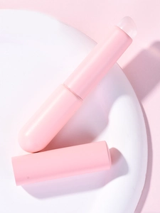 Detail view of the pink silicone lip brush with cap on a white ceramic display stand