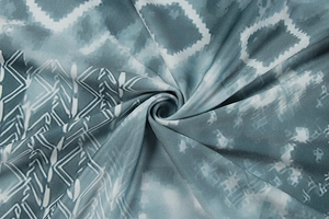 Detail of teal tie-dye fabric with white geometric patterns and soft draping texture