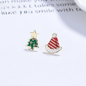 Close-up of asymmetrical Christmas tree and Santa hat silver stud earrings on a magazine