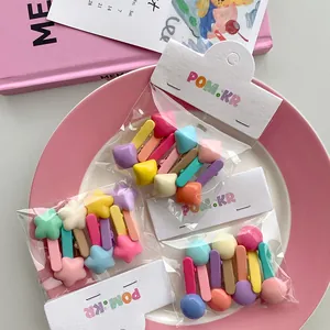 Detail of candy-colored geometric hair clips set in star and round shapes with packaging