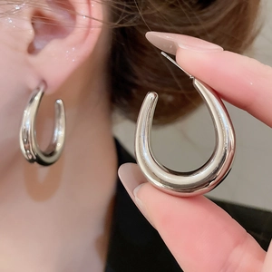 Close-up of polished silver U-shaped hoop earrings showing the mirror finish and pin closure