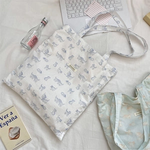 Close-up of cute cartoon cat print canvas tote bags on a cozy white bed background