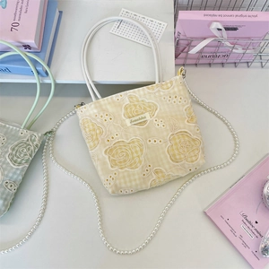 Détail du sac en toile à carreaux jaunes avec broderie rose en dentelle et perles