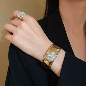 Elegant gold metal bangle and ring set with pearl flower accents on a female model