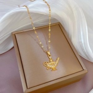 Luxurious gold genie lamp pendant necklace with cubic zirconia on a beige jewelry box