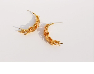 Macro shot of gold tassel feather earrings showing detailed wheat ear leaf textures