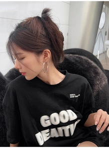 Detail of a casual black cotton T-shirt featuring white GOOD BEAUTY printed text