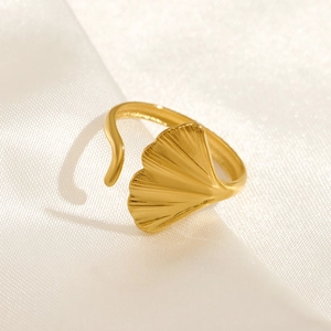 Adjustable golden ginkgo leaf ring in stainless steel resting on white silk fabric