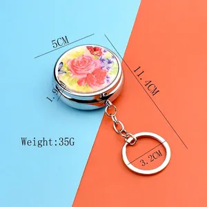 Portable round floral metal pill box keychain with pink rose design and 5cm diameter
