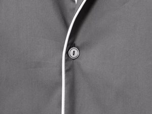 Detailed close-up of dark grey fabric texture with white piping and round button detail