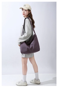 Dettaglio di una grande borsa a tracolla viola in tela di cotone indossata da una modella