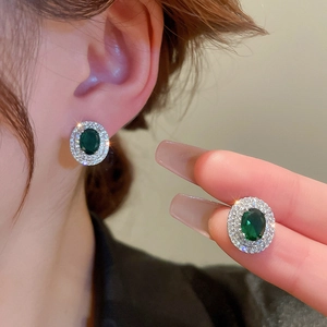 Macro detail of silver geometric oval earrings with emerald zircon and pavé setting