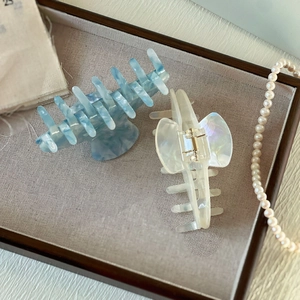 Détail d'une pince à cheveux en acétate marbré bleu et clip papillon irisé