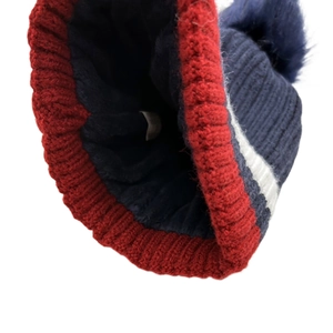 Dettaglio del berretto in maglia blu e rosso con fodera in pile e pompon morbido