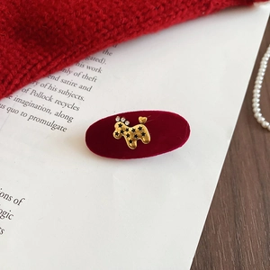 Macro detail of wine red velvet oval hair clip with gold poodle metal embellishment