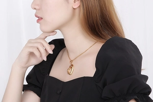 Golden hollow heart pendant necklace with rhinestones worn on a black square neck top