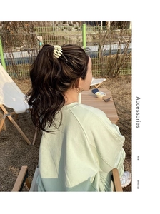 Detail of a large pale yellow wavy bird nest hair clip worn in a relaxed outdoor park setting