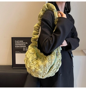Detail of green quilted velvet tote bag with ruffled handle shown in indoor lifestyle setting