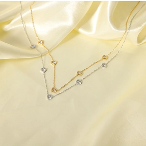 Detail of gold and silver stainless steel necklaces with heart-shaped zircon pendants