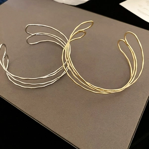 Detail of overlapping thin metal wire layers in gold and silver finish on wavy bangle