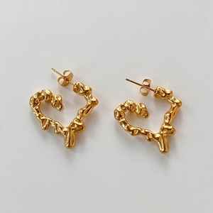 Detail of gold heart earrings featuring lava textured irregular surface and minimalist style