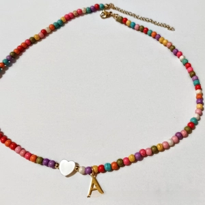Detail of beaded necklace with colorful beads, heart charm, and golden initial A pendant