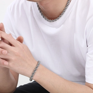 Close-up of a silver stainless steel twist chain necklace and bracelet worn by a model