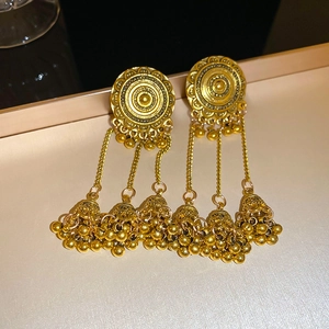 Detailed macro shot of vintage gold phoenix crescent tassel earrings on a metal tray