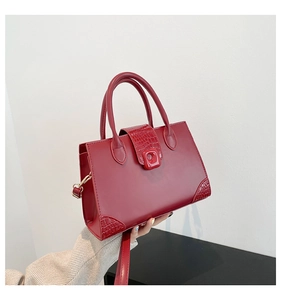 Detail of red leather handbag with crocodile pattern texture on the flap and corners