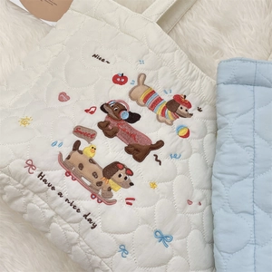 Gros plan d'un sac cabas matelassé blanc avec broderie chien et textures de cœurs