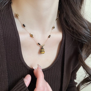 Close-up of tiger eye stone gourd pendant necklace on model with beaded chain detail