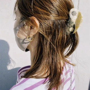 Detail of large marble pattern hair claw clip on brunette hair in a half-up style