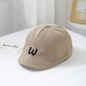 Detailed embroidery of black letter W on beige cotton child sun hat for summer
