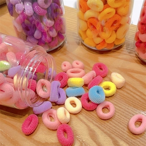 Colorful macaron elastic hair ties in a transparent bottle on a rustic wooden desk