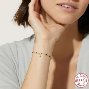 Close-up of S925 sterling silver gold bracelet with black beads and small pearl